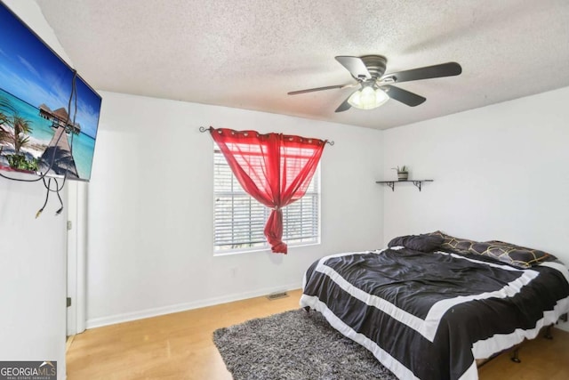 bedroom with visible vents, light wood-style floors, ceiling fan, a textured ceiling, and baseboards