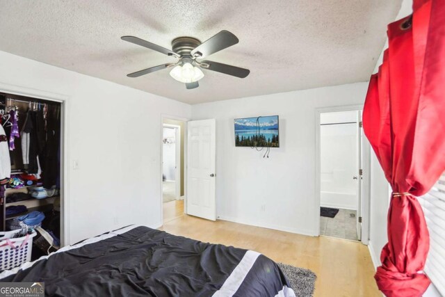 bedroom featuring ceiling fan, connected bathroom, a textured ceiling, and wood finished floors