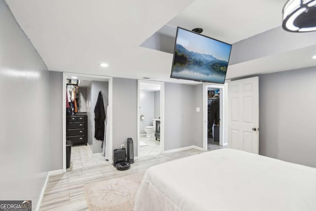 bedroom featuring a walk in closet, a closet, baseboards, and ensuite bathroom
