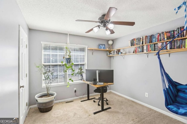 carpeted home office featuring ceiling fan, baseboards, and a textured ceiling