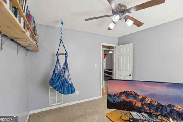 carpeted bedroom featuring baseboards, visible vents, ceiling fan, and a textured ceiling