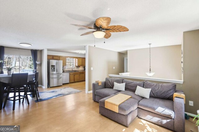 living room with light wood-type flooring, baseboards, and a ceiling fan