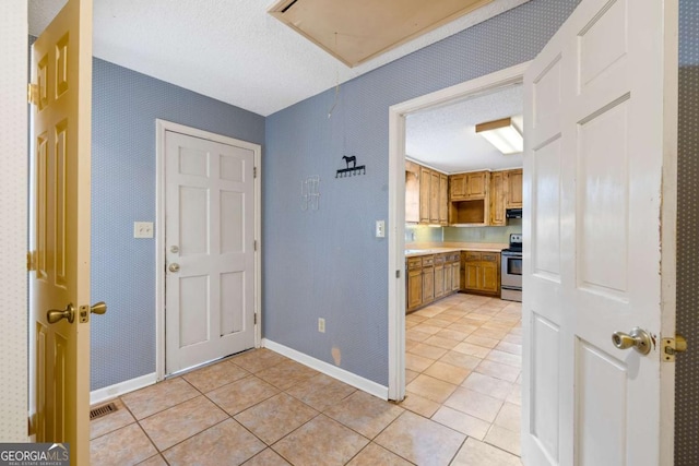 kitchen featuring light tile patterned floors, stainless steel electric stove, light countertops, visible vents, and baseboards