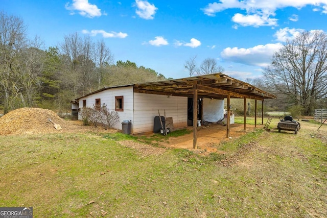 view of side of home featuring a carport, an outbuilding, a yard, and an outdoor structure