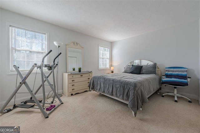 bedroom featuring a textured ceiling, baseboards, and light colored carpet