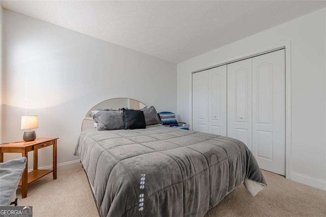 bedroom with a textured ceiling, a closet, carpet flooring, and baseboards