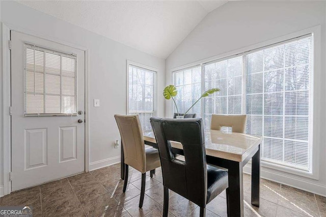 dining room featuring lofted ceiling and baseboards