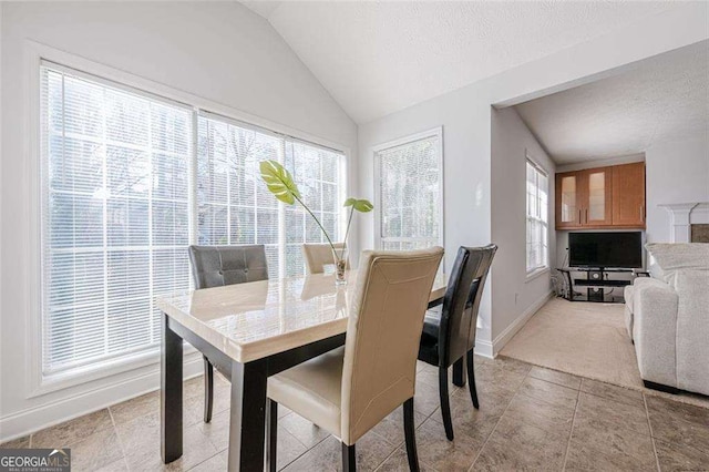 dining space featuring lofted ceiling, light tile patterned flooring, a textured ceiling, and baseboards