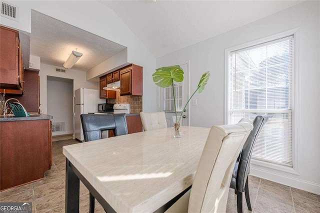 dining space featuring vaulted ceiling, visible vents, and baseboards