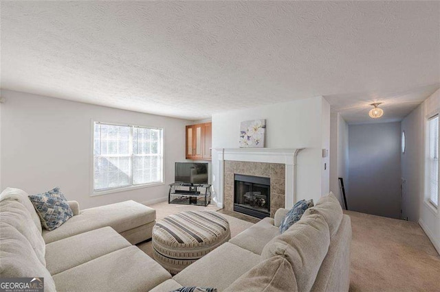 living room with light carpet, a textured ceiling, and a tiled fireplace