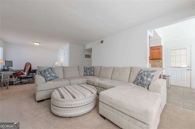 living area featuring a textured ceiling, visible vents, and light colored carpet