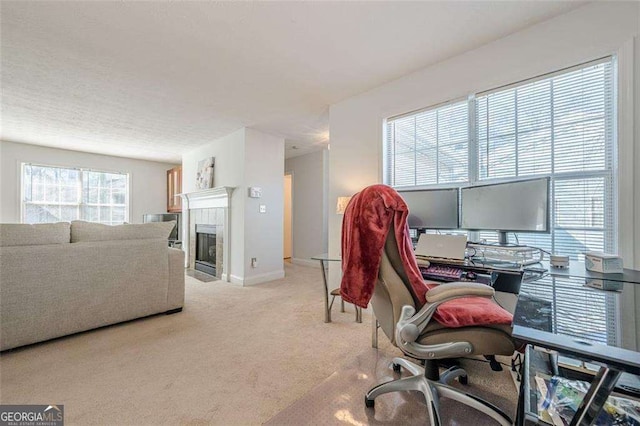 office with carpet floors, a tiled fireplace, and baseboards