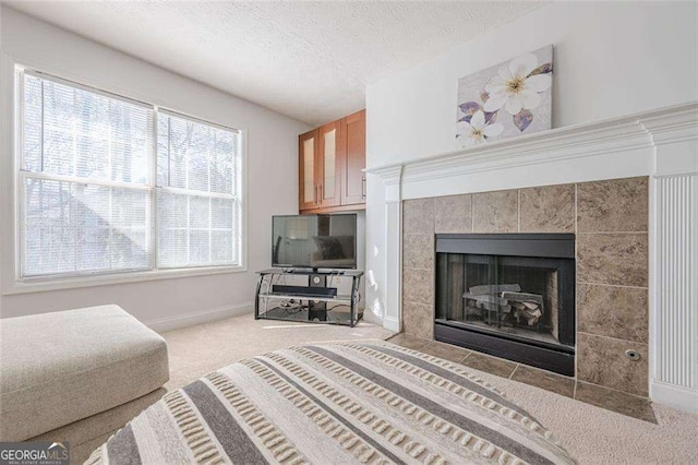 interior space featuring a tile fireplace, carpet flooring, a textured ceiling, and baseboards