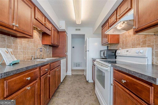 kitchen with white appliances, a sink, visible vents, and under cabinet range hood