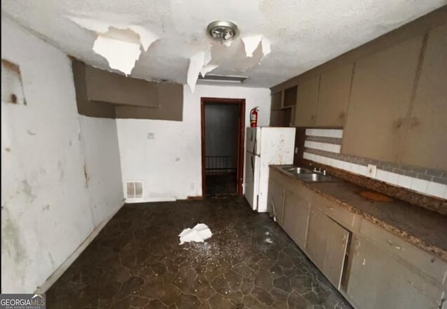 1188 Sunnydale Dr, Macon, GA 31217 - kitchen featuring visible vents, backsplash, freestanding refrigerator, a sink, and a textured ceiling