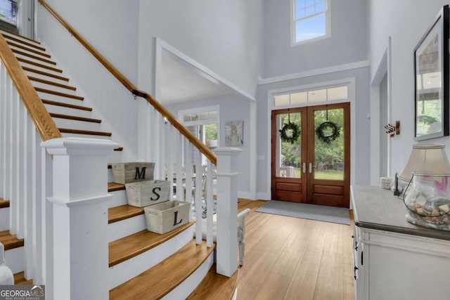 foyer entrance featuring stairs, a healthy amount of sunlight, a high ceiling, and light wood-style floors