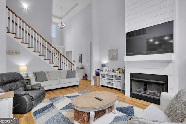 living room with a high ceiling, a fireplace, stairway, and wood finished floors