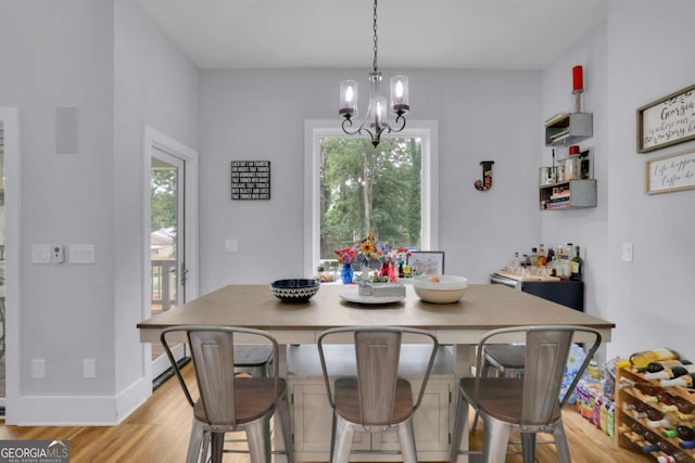 dining space with baseboards, light wood-style flooring, and a notable chandelier