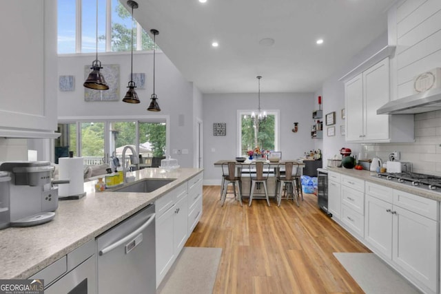 kitchen with stainless steel appliances, white cabinets, a sink, light wood-type flooring, and beverage cooler