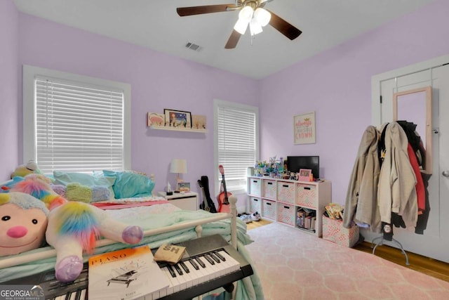 bedroom with a ceiling fan, visible vents, and wood finished floors