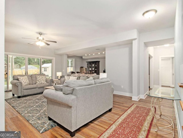 living room with ceiling fan, baseboards, and wood finished floors