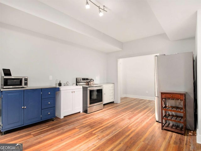 kitchen featuring stainless steel appliances, baseboards, light countertops, blue cabinetry, and light wood-type flooring