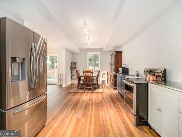 kitchen featuring baseboards, light wood-style flooring, appliances with stainless steel finishes, and track lighting