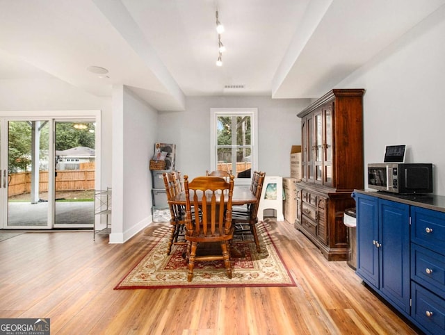 dining area featuring light wood-style floors, baseboards, and rail lighting