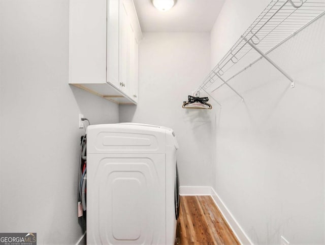 laundry area with light wood-style flooring, cabinet space, and baseboards