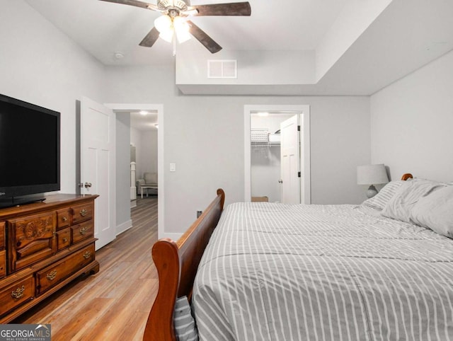 bedroom with ceiling fan, light wood finished floors, visible vents, and baseboards