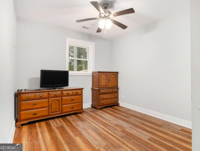 interior space featuring a ceiling fan, visible vents, light wood-style flooring, and baseboards