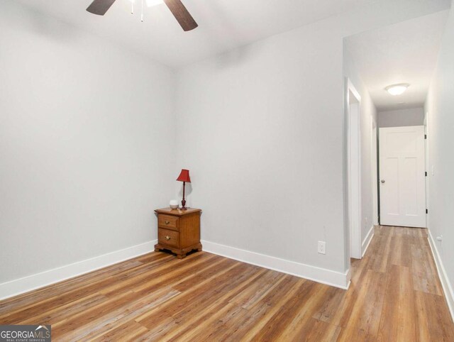 empty room featuring light wood-style floors, baseboards, and a ceiling fan