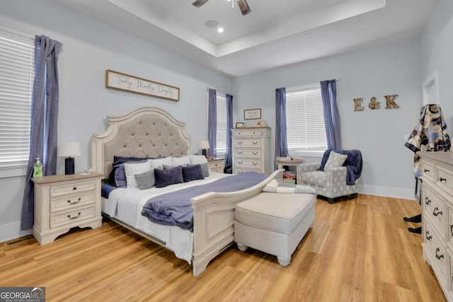 bedroom featuring baseboards, light wood-style flooring, ceiling fan, a tray ceiling, and recessed lighting