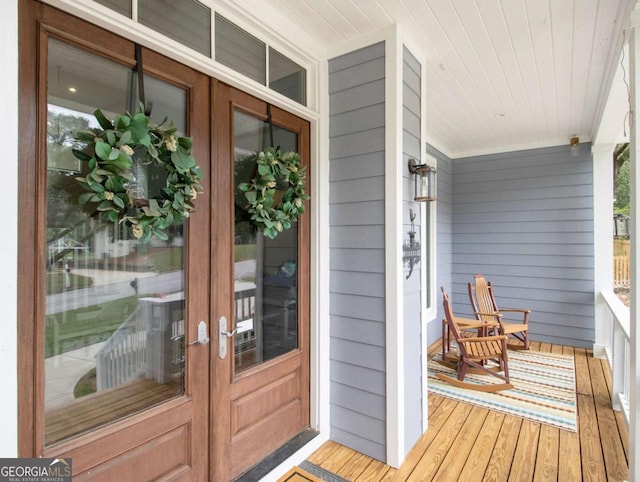 view of exterior entry featuring french doors and a porch