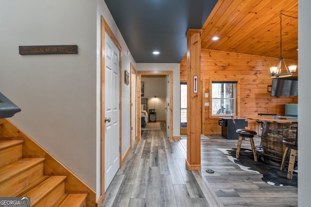 interior space featuring recessed lighting, stairway, wood walls, wood finished floors, and a chandelier