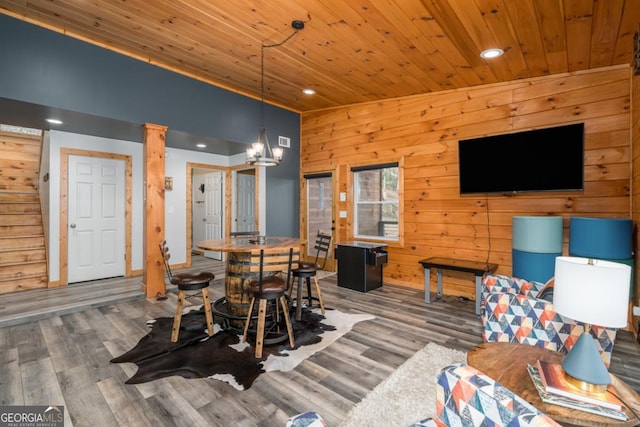 dining space with wooden ceiling, wooden walls, and wood finished floors