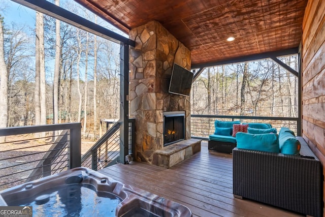 wooden terrace featuring an outdoor stone fireplace and hot tub deck surround