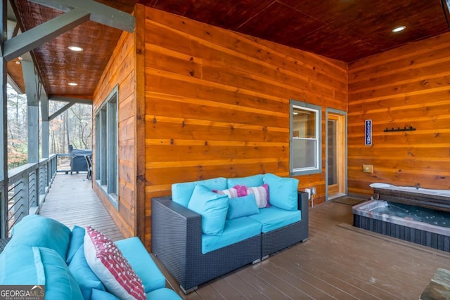 wooden terrace with an outdoor hot tub and an outdoor hangout area