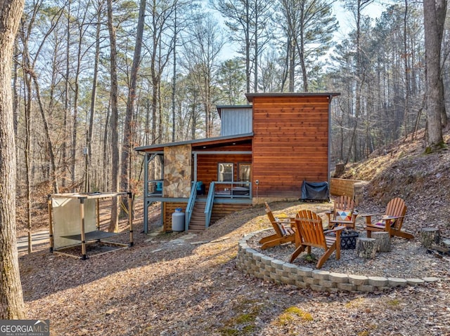 view of patio / terrace with an outdoor fire pit and a wooded view