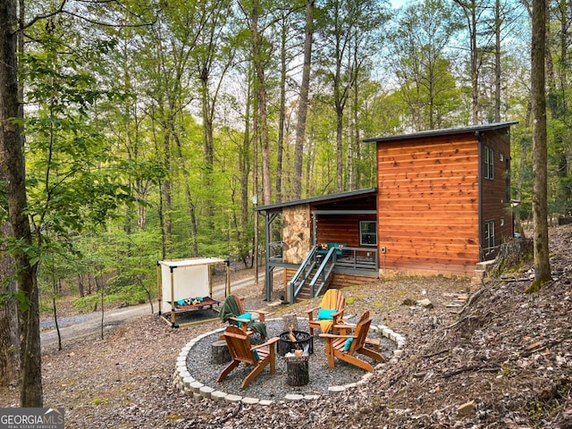 view of yard featuring a fire pit and a view of trees