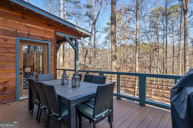 wooden deck with outdoor dining space and grilling area