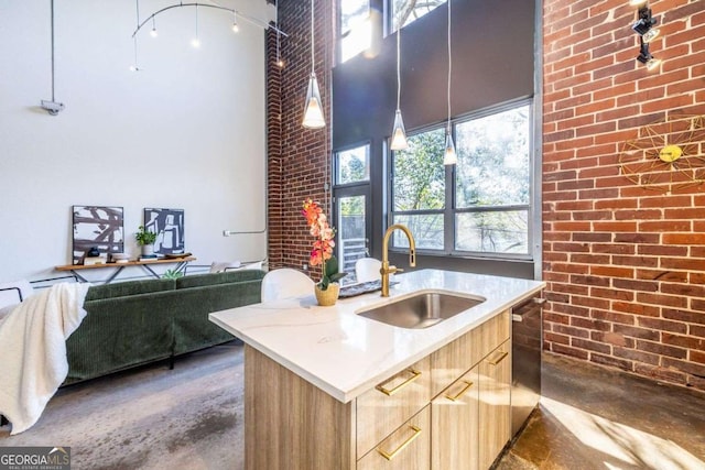 kitchen featuring light brown cabinets, brick wall, a sink, a towering ceiling, and finished concrete floors