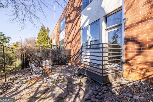 exterior space with a patio area, fence, and brick siding