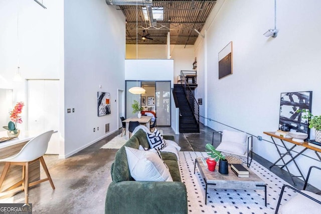 living room with concrete flooring, a high ceiling, visible vents, and baseboards