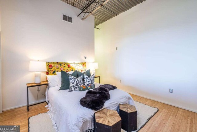 bedroom with a towering ceiling and wood finished floors