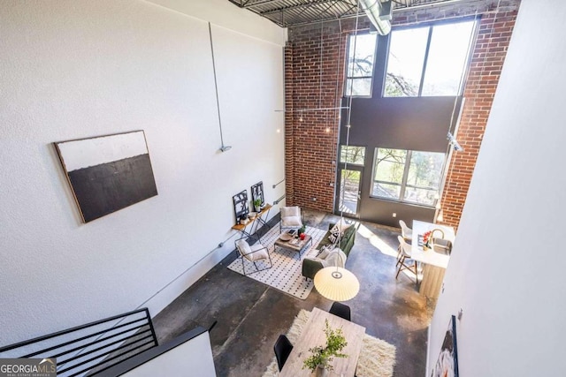 living room with brick wall, concrete floors, and a high ceiling