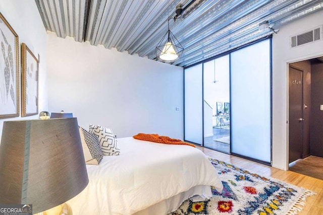 bedroom featuring access to outside, floor to ceiling windows, visible vents, and wood finished floors