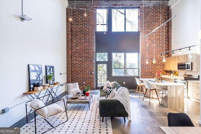 living area featuring brick wall, a high ceiling, and finished concrete floors