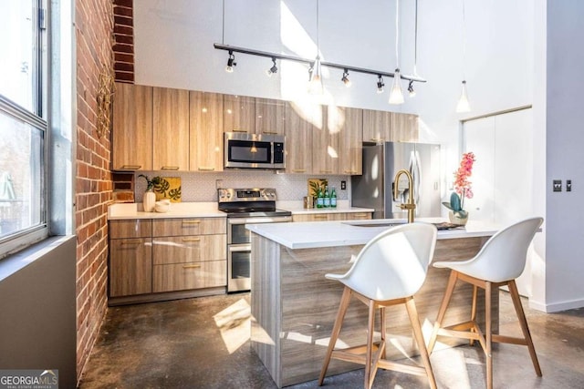 kitchen featuring stainless steel appliances, light countertops, concrete flooring, and backsplash