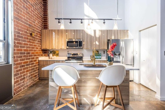 kitchen featuring decorative light fixtures, stainless steel appliances, light countertops, decorative backsplash, and finished concrete floors